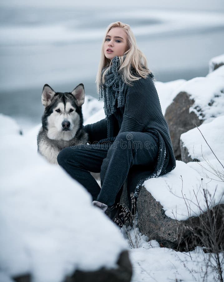 Girl with dog Malamute among rocks in winter.