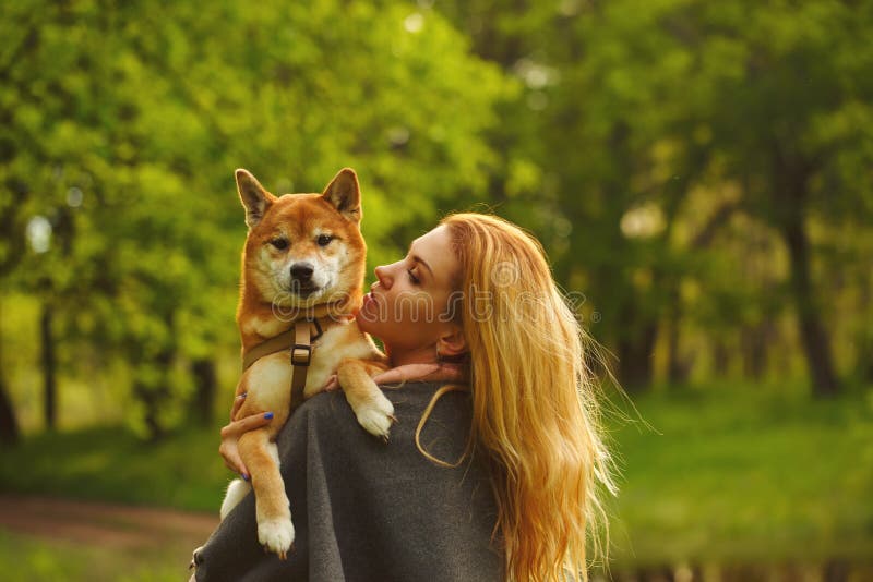 Girl and dog Shiba Inu hug.