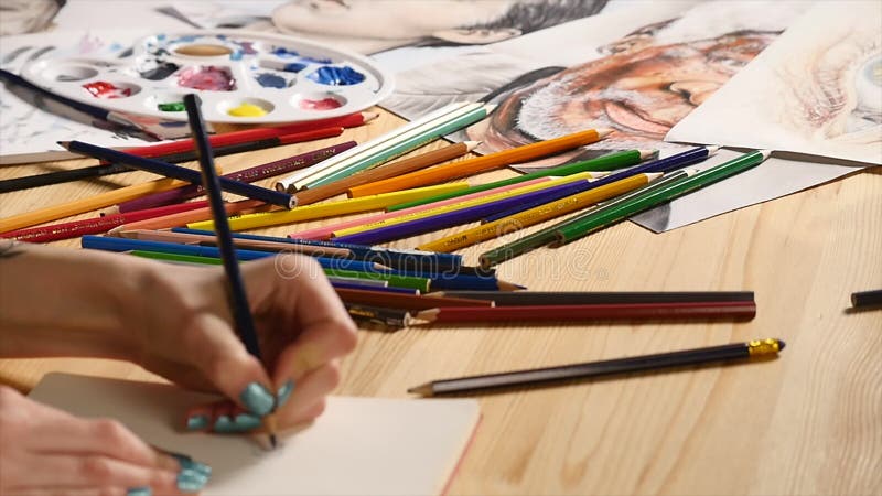 The girl draws pencil sketch on paper. Close up