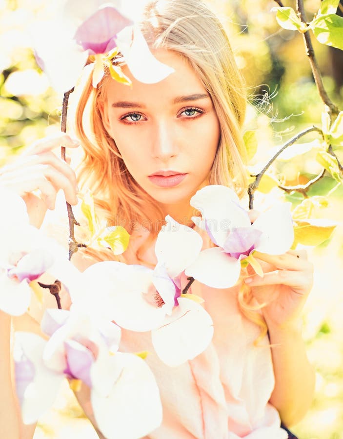 Girl on dreamy face, tender blonde near magnolia flowers, nature background. Young woman enjoy flowers in garden. Spring