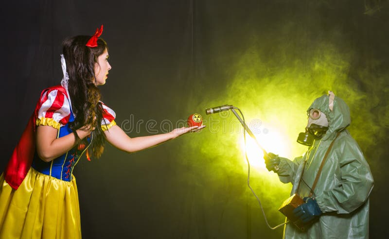 Woman dressed as fairytale character holds Radioactive atomic nuclear ionizing radiation danger warning symbol on apple. Girl dressed as fairytale character royalty free stock photos Woman dressed as fairytale character holds Radioactive atomic nuclear ionizing radiation danger warning symbol on apple. Girl dressed as fairytale character royalty free stock photos
