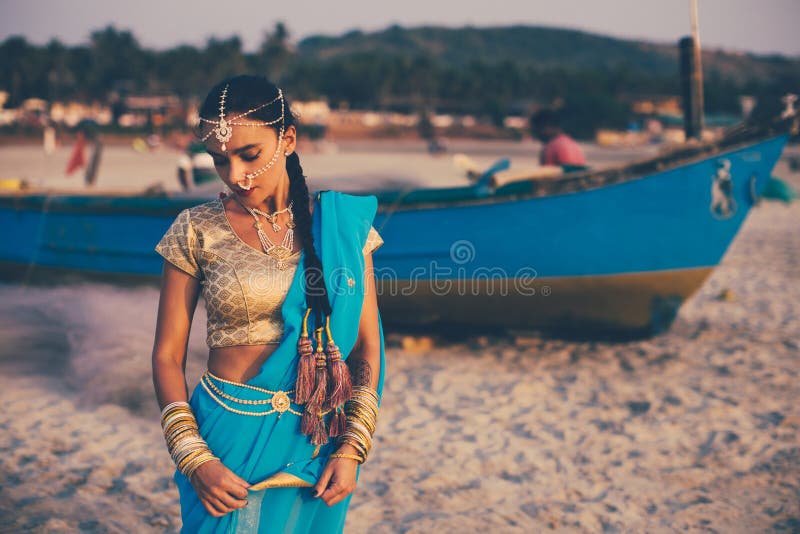 A girl dressed in indian saree near the fisherman`s boat