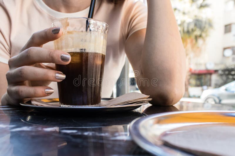 A girl drinking cold coffee while talking at hot summer day.