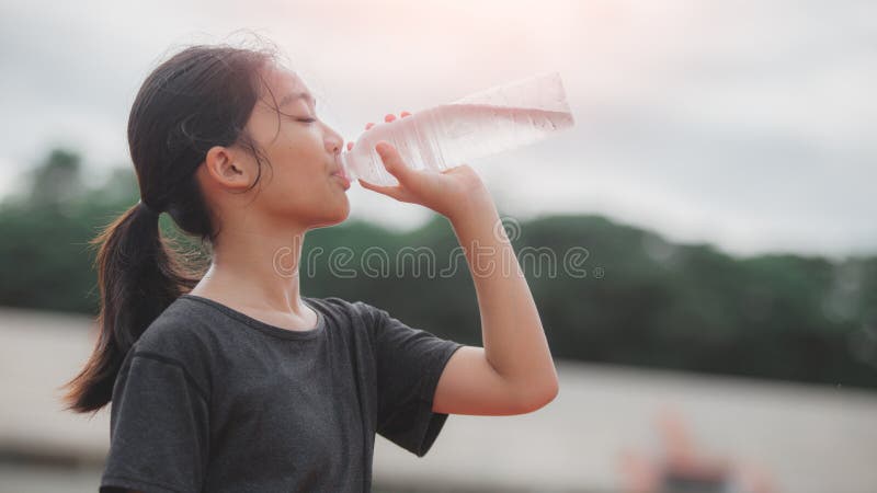 A girl drinking water from a bottle stock image