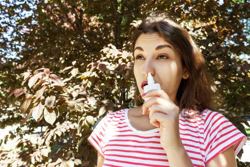 Girl drips blocked nose from allergy. Woman with Respiratory Spray for nose in Spring Blooming. Portrait of a woman having respira