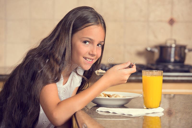 Girl eating cereal with milk drinking orange juice for breakfast stock photo Girl eating cereal with milk drinking orange juice for breakfast stock photo