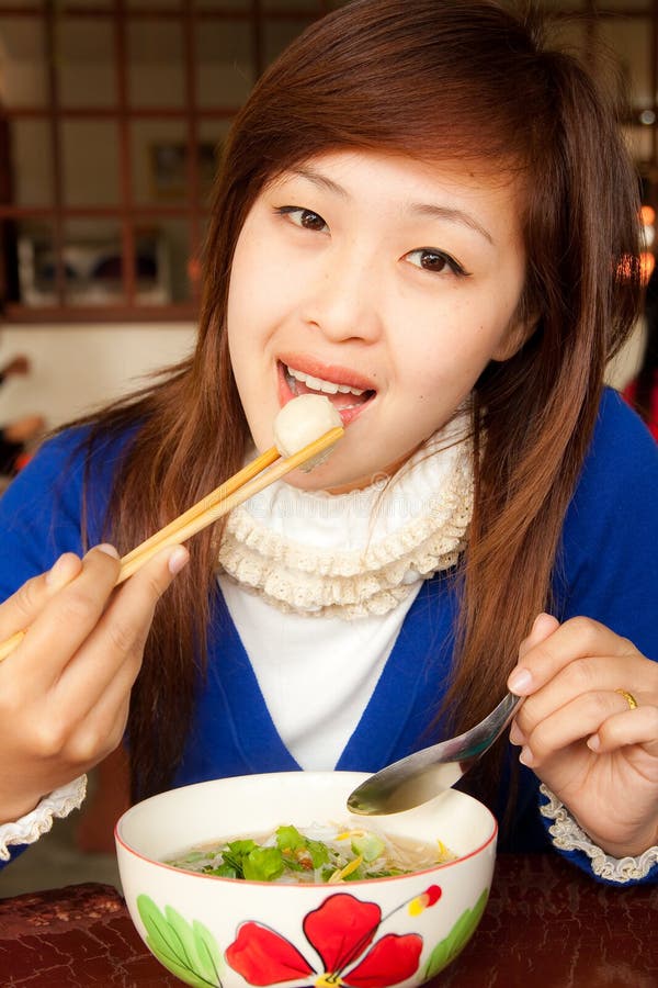 Girl eating meatball with shopstick and spoon