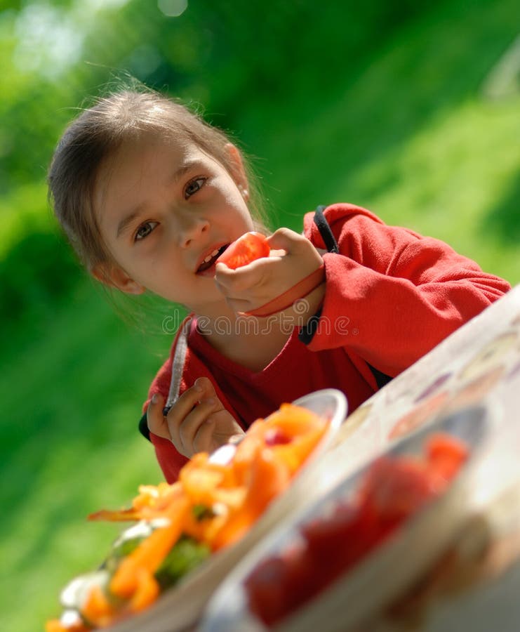 The girl eats a tomato