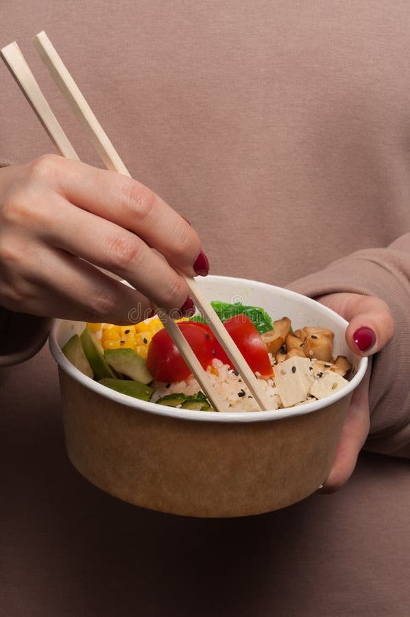 The girl eats a vegetarian poke. vertical frame royalty free stock image