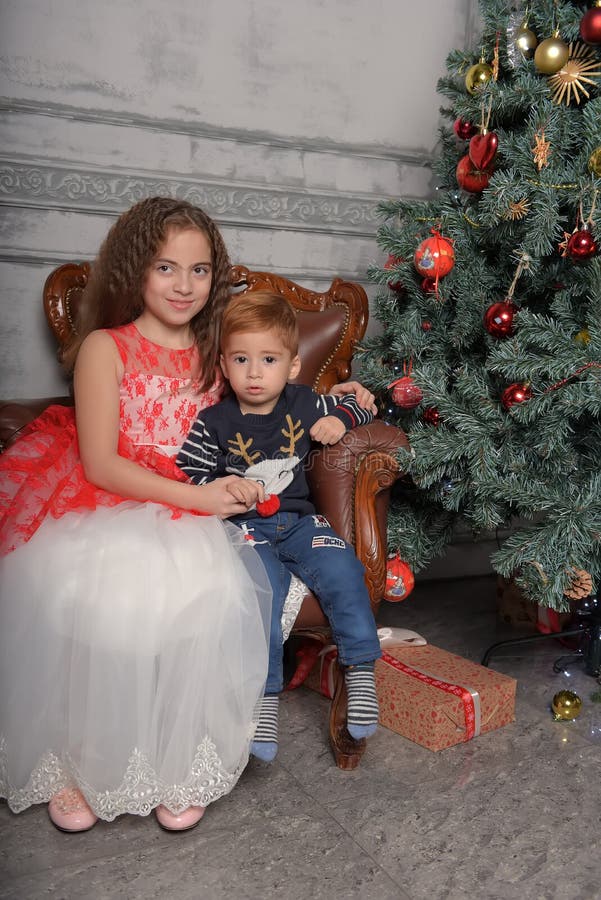 Girl in elegant dress near the Christmas tree with her brother royalty free stock photo Girl in elegant dress near the Christmas tree with her brother royalty free stock photo