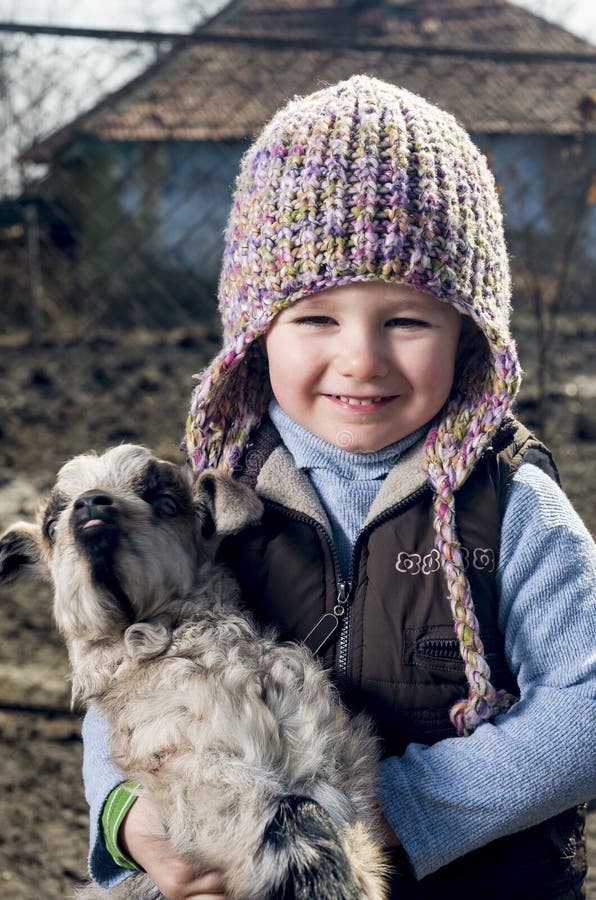 Tři roky stará dívka holding / všeobjímající goatling.