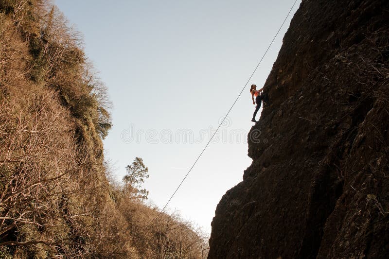 Girl equipped with a rope climbing on the sloping rock and looking up stock photography Girl equipped with a rope climbing on the sloping rock and looking up stock photography