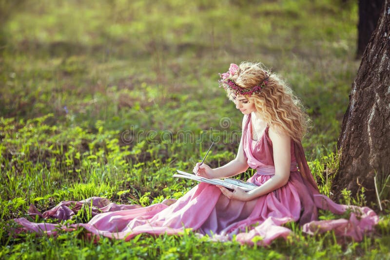 Girl in a fairy dress sitting under a tree in the woods