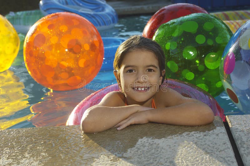 Girl with Floating Ring and Beach Balls in Swimming Pool Stock Photo