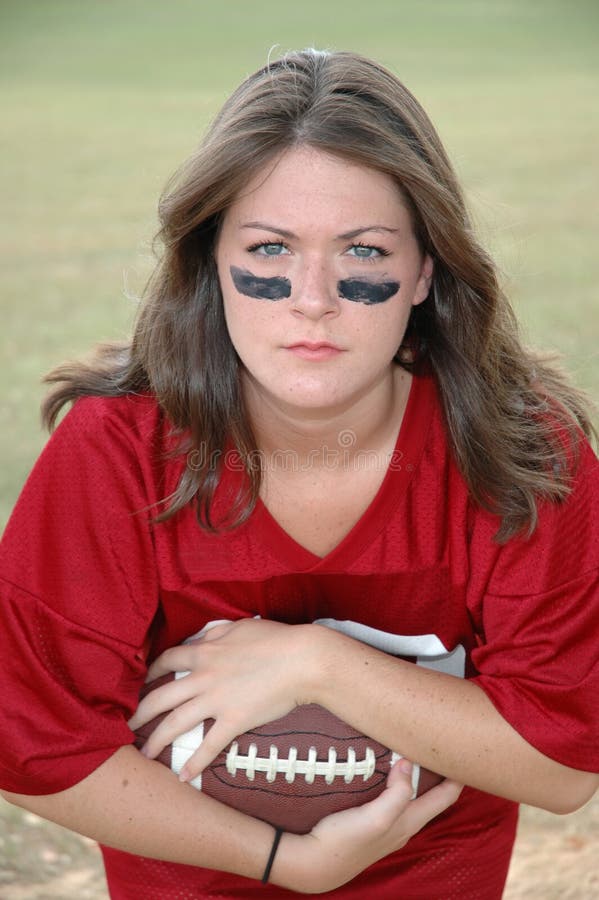 Young woman holding football and helmet. War paint. Young woman holding football and helmet. War paint.