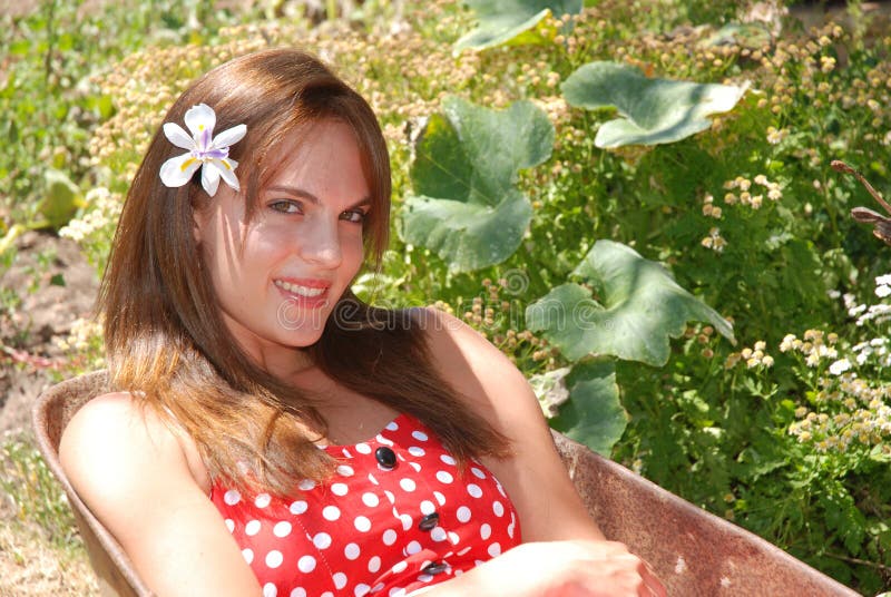Una bella caucasica bianco giovane donna sorridente felice espressione del viso, indossando un abito estivo e un fiore tra i suoi lunghi capelli bruna.