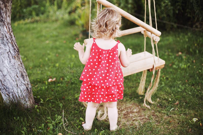 Girl in the garden playing with swings. baby playing in the garden stock photos Girl in the garden playing with swings. baby playing in the garden stock photos