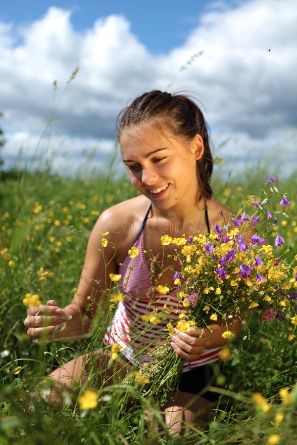 Girl is gathering flowers in a field