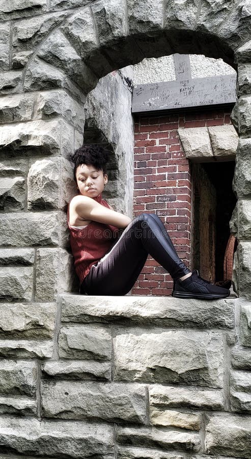 African American teen girl sitting alone in a window stock photography African American teen girl sitting alone in a window stock photography
