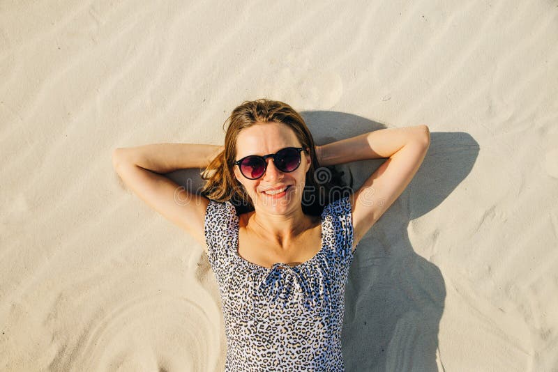 Girl with Glasses is Relaxing by Laying Down on the Beach. Top View