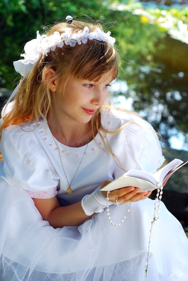 Ritratto di ragazza in abito bianco e corona, andando per la prima volta la santa comunione in posa nel parco.