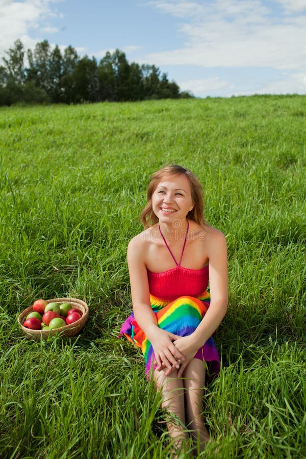 Girl on the grass next to a basket of apples royalty free stock images