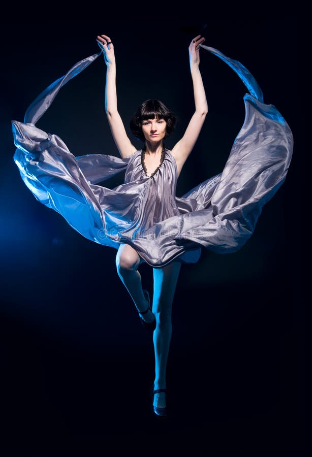 Girl in a gray dress flying on a black