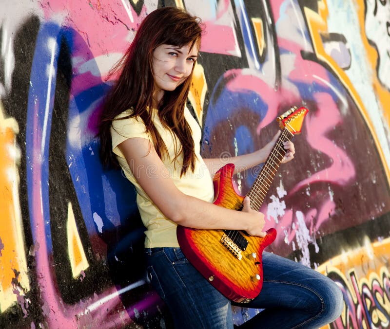 Girl with guitar and graffiti wall