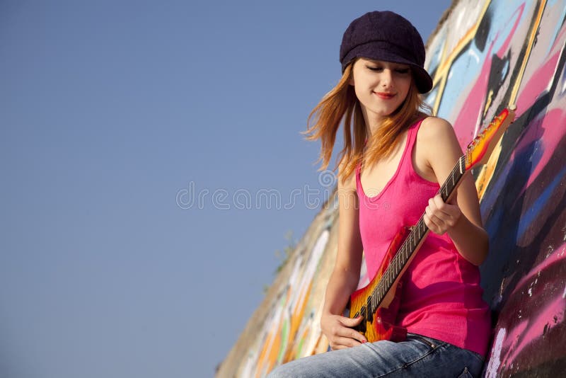 Girl with guitar and graffiti wall