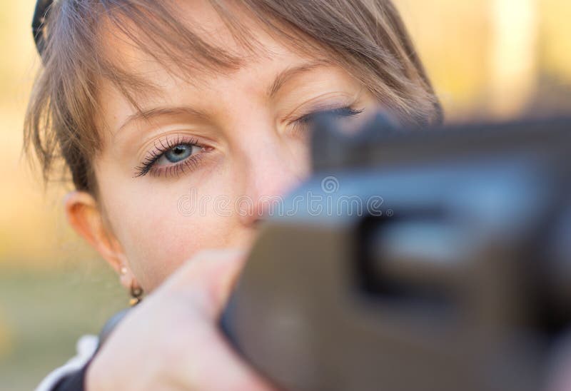 A young girl with a gun for trap shooting and shooting glasses aiming at a target