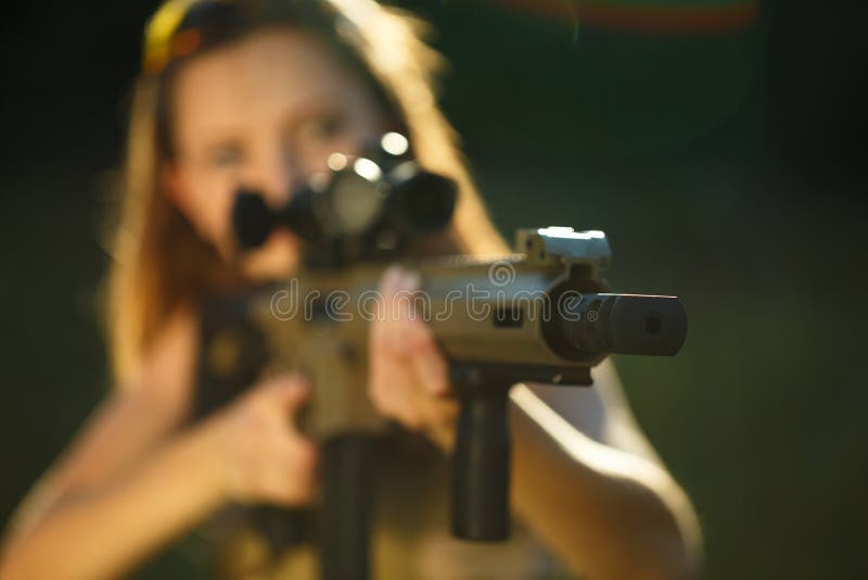 A young girl with a gun for trap shooting aiming at a target. Short depth of field, focus on the barrel