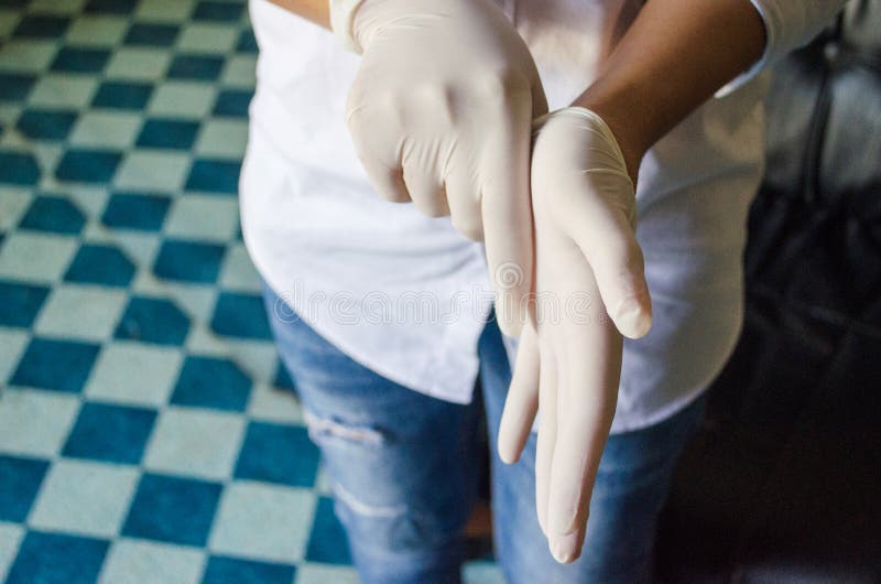 Girl hand wearing latex gloves on dark background.