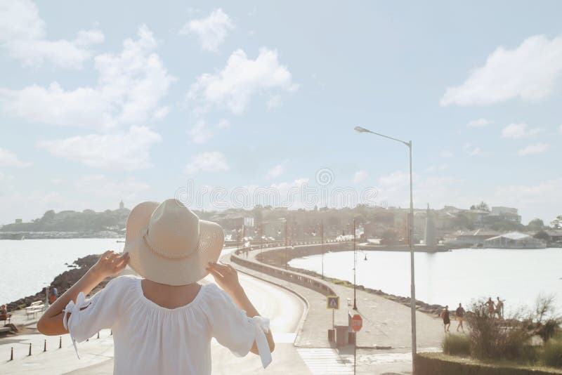 Girl in a hat looks at the panorama of the old town in Bulgaria. Woman and road to Nesebar city