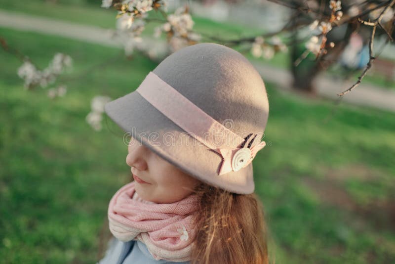 Girl in a hat in a lush garden