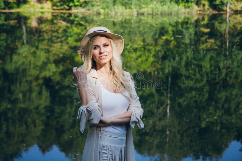 Girl in a hat resting on the autumn lake on the bridge