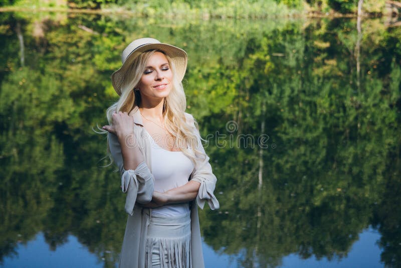 Girl in a hat resting on the autumn lake on the bridge