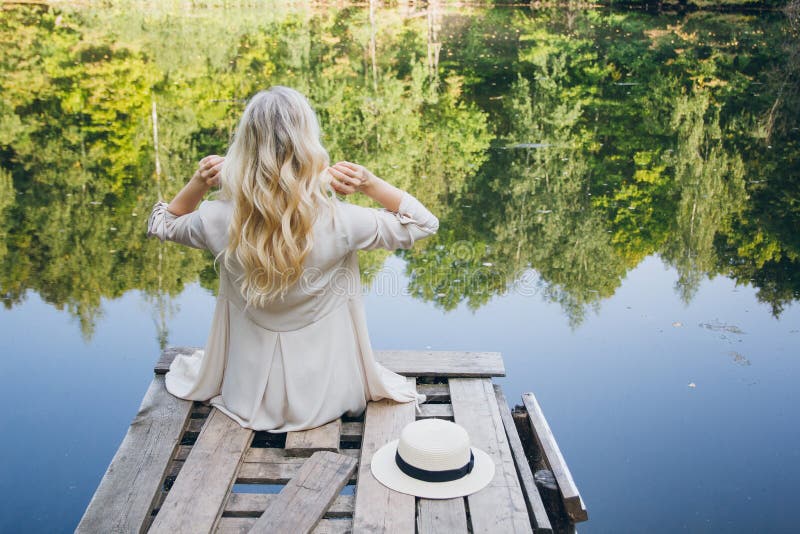 Girl in a hat resting on the autumn lake on the bridge