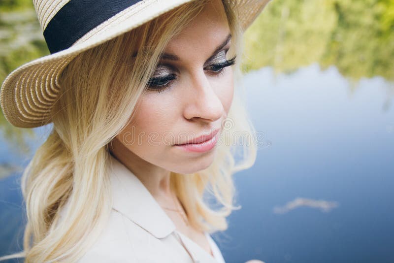 Girl in a hat resting on the autumn lake on the bridge