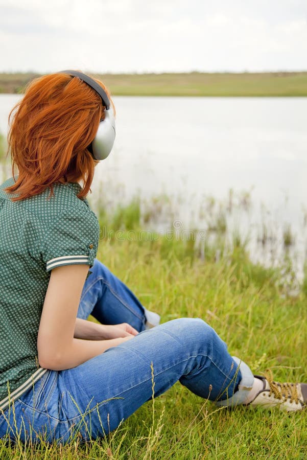 Girl with headphones at grass in spring time.