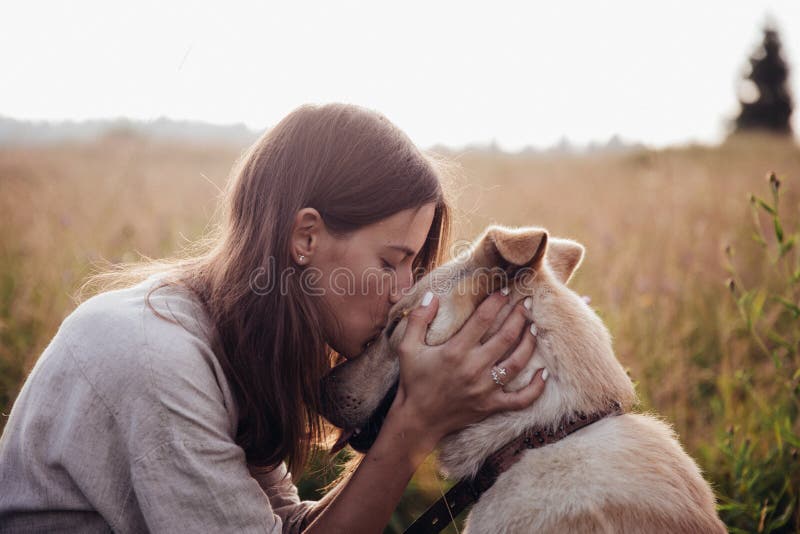 Human and a dog. Girl and her friend dog on the straw field background. Beautiful young woman relaxed and carefree