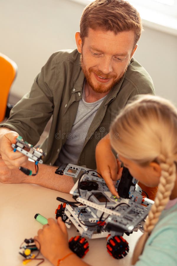 Girl and her teacher turning on the robotic car. royalty free stock image