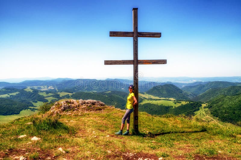 Dívka tramp pózuje s křížem na vrcholu kopce Strážov na Slovensku