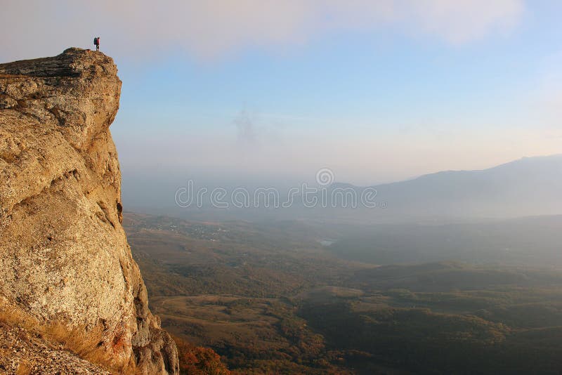 Girl hiker standing on edge of the cliff and enjoying valley view from top of the mountain