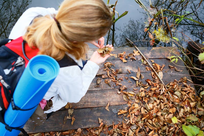 Girl hiker on a wooden platform in the autumn river