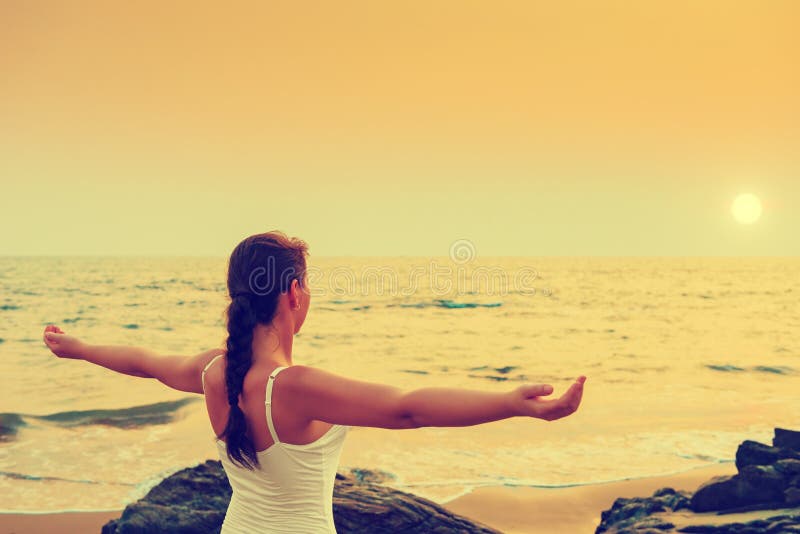 Girl with his hands spread apart at sunset by the sea.