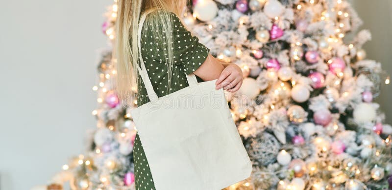 The girl is holding blank cotton eco tote bag, design mockup. Eco concept. Xmas. The girl is holding blank cotton eco tote bag, design mockup. Eco concept. Xmas.