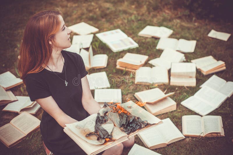 A girl holding a book burning in nature in summer garden royalty free stock image A girl holding a book burning in nature in summer garden royalty free stock image
