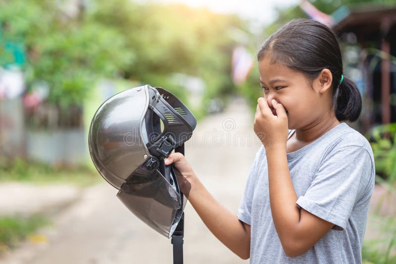 Girl holding brown helmet of motorcycle and smelling. Old helmet