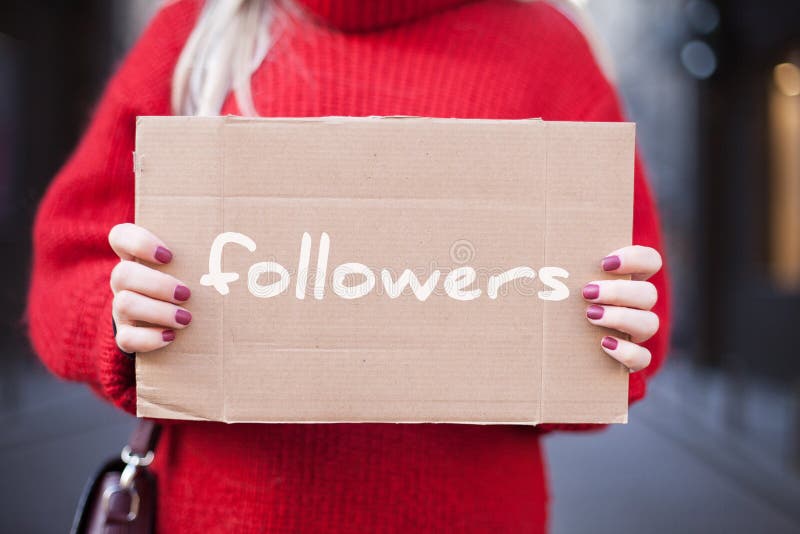 The girl is holding a cardboard tablet in her hands with the inscription `followers. stock photography The girl is holding a cardboard tablet in her hands with the inscription `followers. stock photography