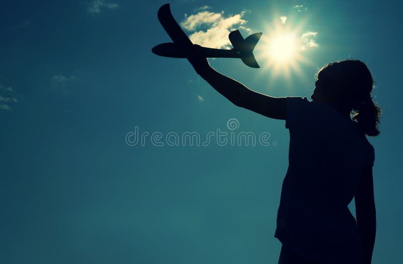 Girl holding a children`s plane in outstretched hand against the background of the sun - concept of success, desire for a dream, royalty free stock photography Girl holding a children`s plane in outstretched hand against the background of the sun - concept of success, desire for a dream, royalty free stock photography